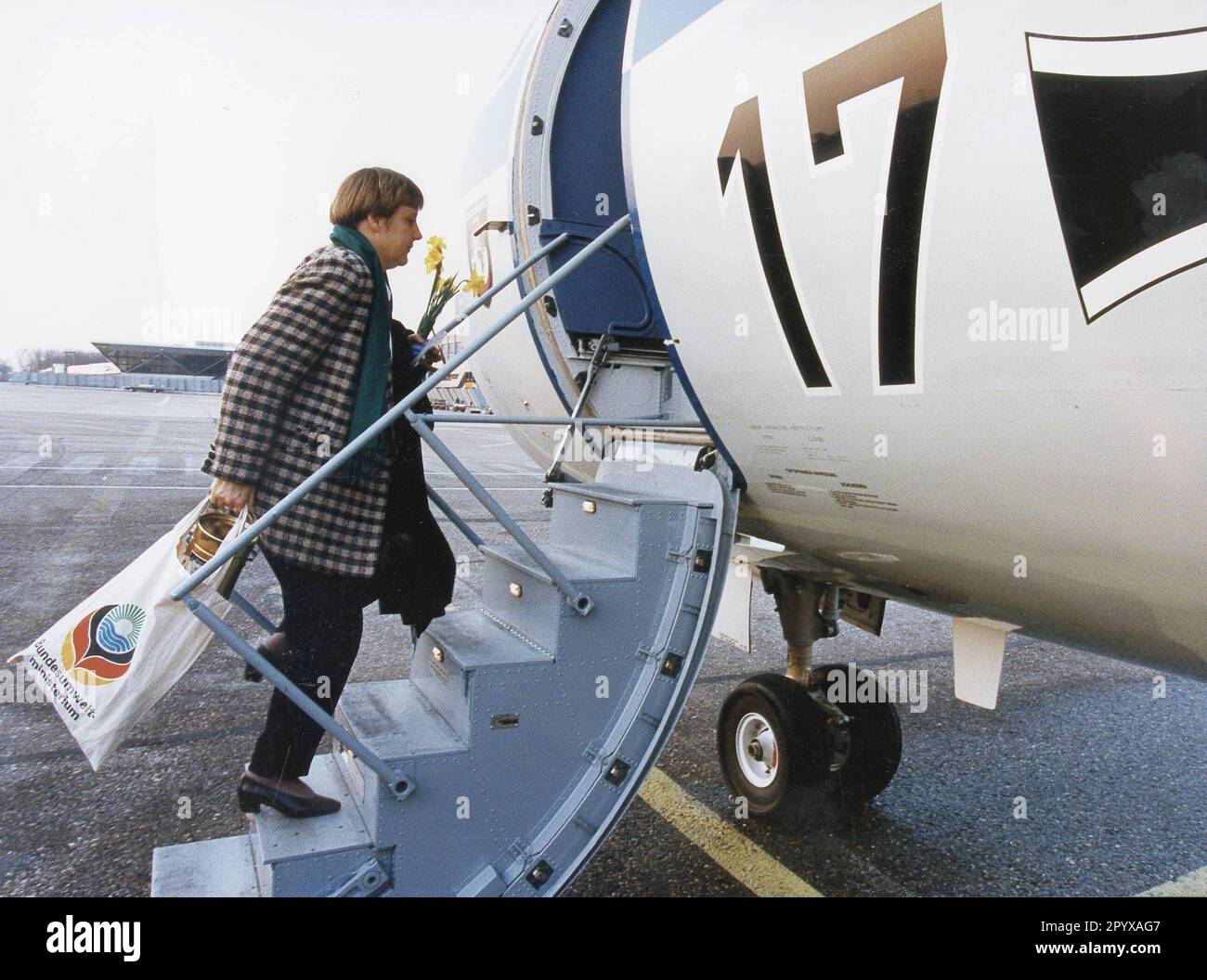 La ministre de l'Environnement Angela Merkel (CDU) est montée à bord de l'avion avec un sac du ministère fédéral de l'Environnement, un pot de miel et un bouquet de jonquilles dans sa main. [traduction automatique] Banque D'Images