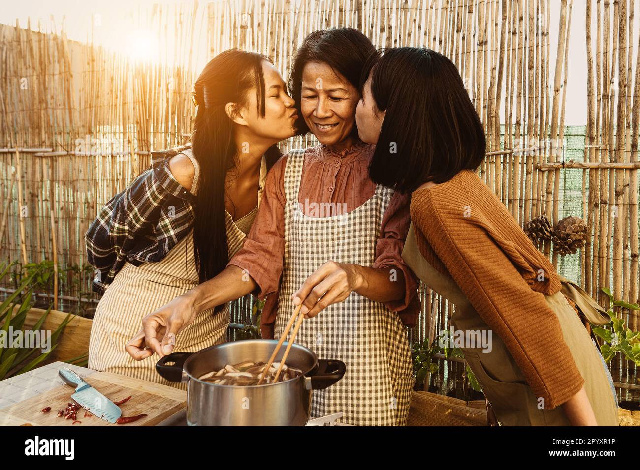 Mère d'asie du Sud-est avec ses filles ayant plaisir à préparer la recette de la nourriture thaïlandaise ensemble dans le patio de la maison Banque D'Images