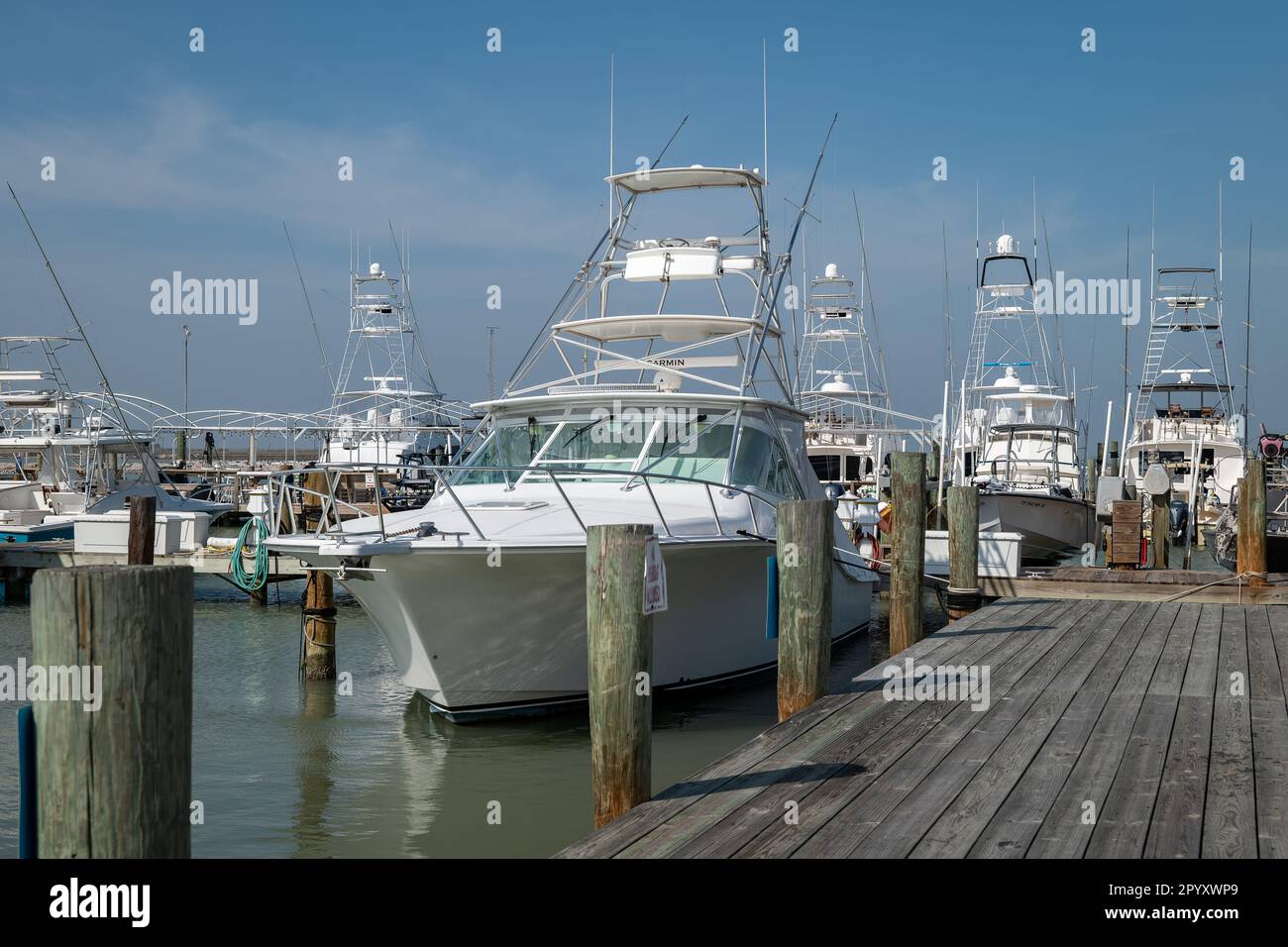 PORT ARANSAS, TX - 22 FÉV 2023: Bateau de pêche sportive ou yacht attaché par corde au pirage de bois au quai dans la marina par une journée ensoleillée. Banque D'Images