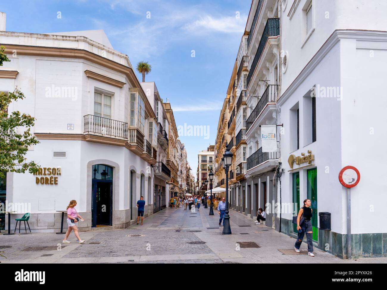 Les touristes se délectent d'une longue rue pavée, sous un ciel bleu vif, à Cadix, en Espagne Banque D'Images