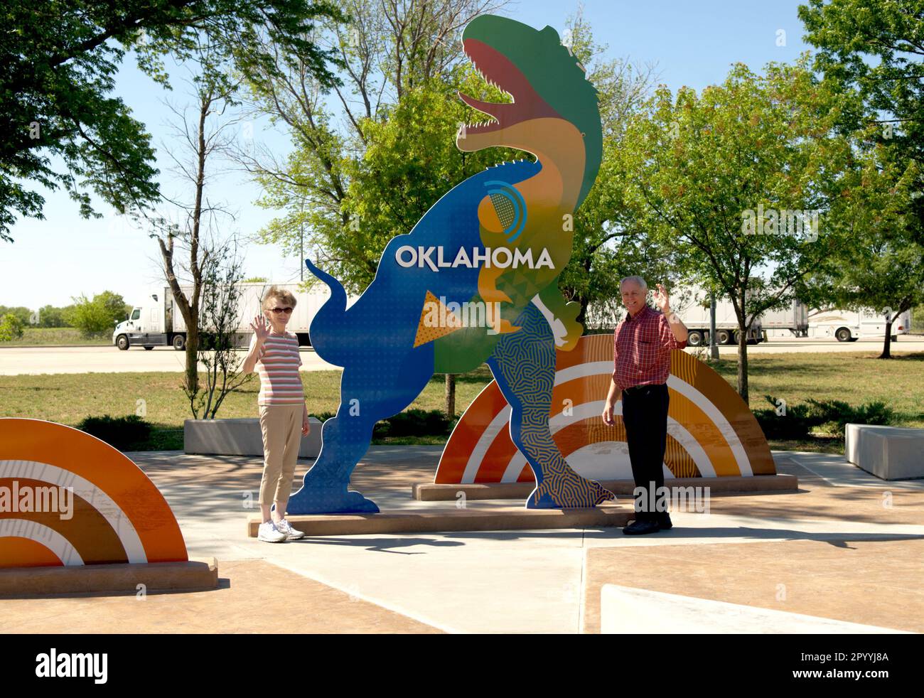 Un couple Senior se fait passer devant la caméra, debout à côté du dinosaure coloré au centre d'accueil de l'Oklahoma, aux États-Unis. Banque D'Images