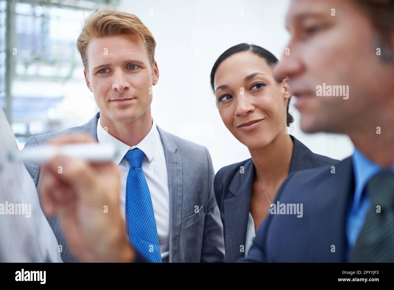 Trouver des idées sur la façon de développer leur activité. Un homme d'affaires écrivant sur un tableau de conférence alors que ses collègues se tiennent à côté. Banque D'Images
