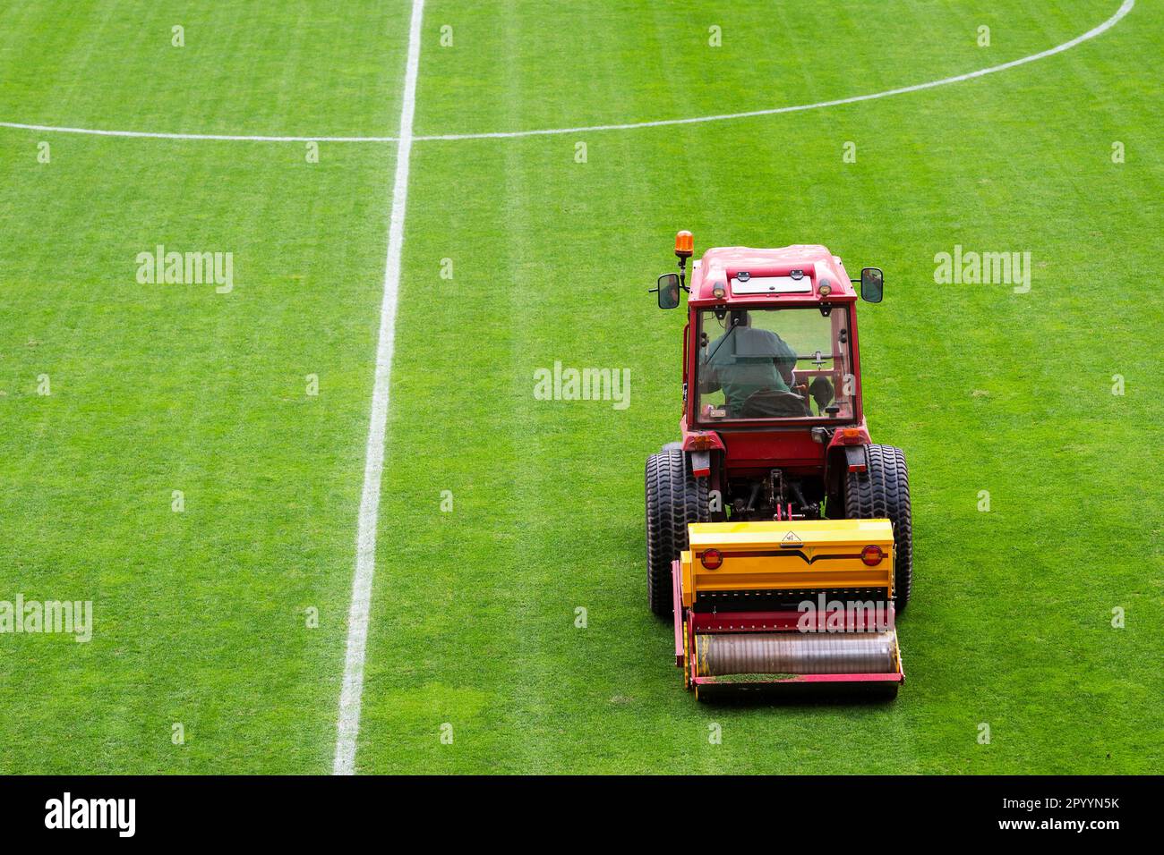 Un homme dans un tracteur équipé d'un semoir à disque a semé de l'herbe sur le terrain de football Banque D'Images