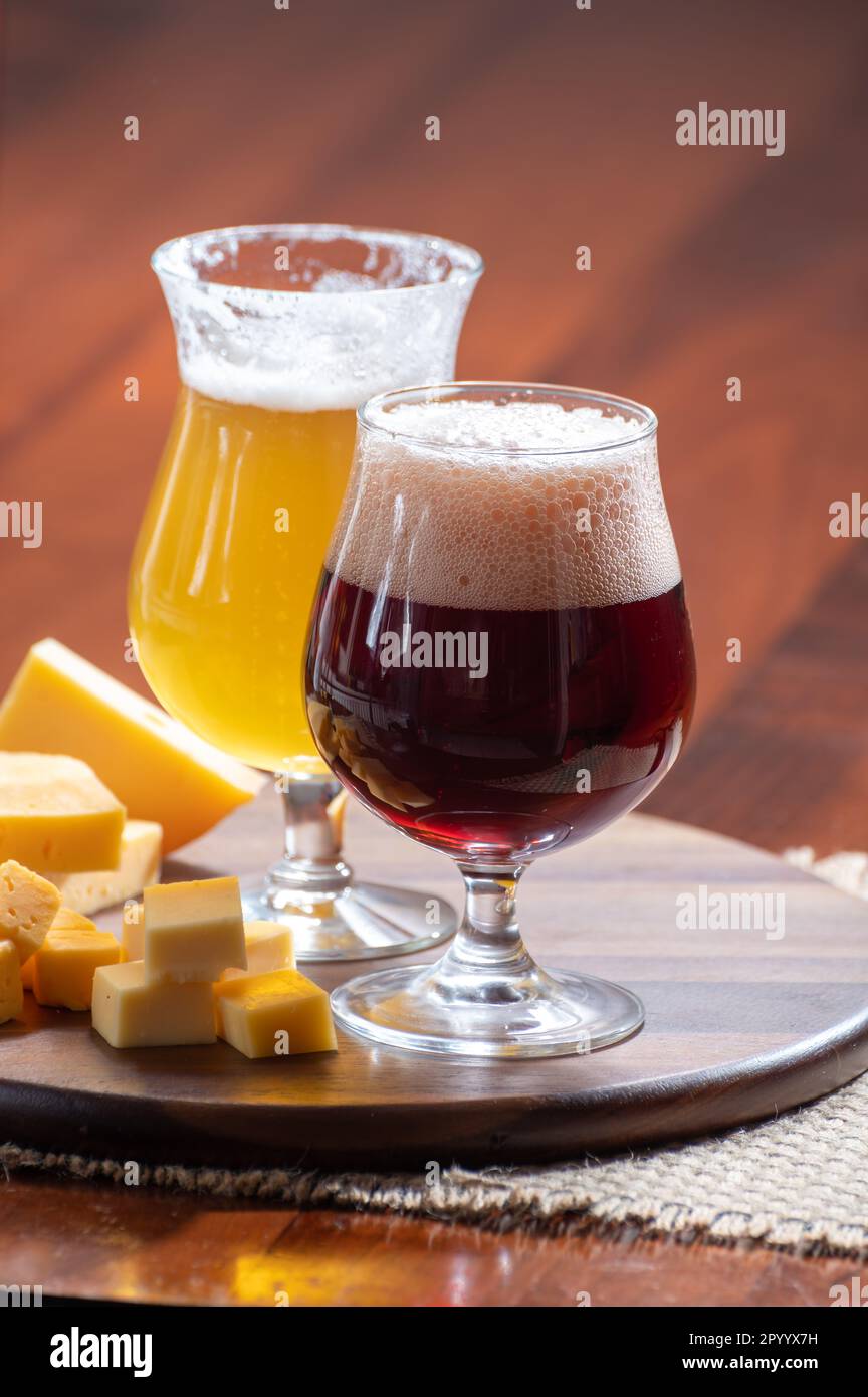 Verres de bière blonde jaune belge et brune foncée fabriqués en abbaye et en bois avec une variété de fromages belges, plats et bières assortis en Belgique Banque D'Images
