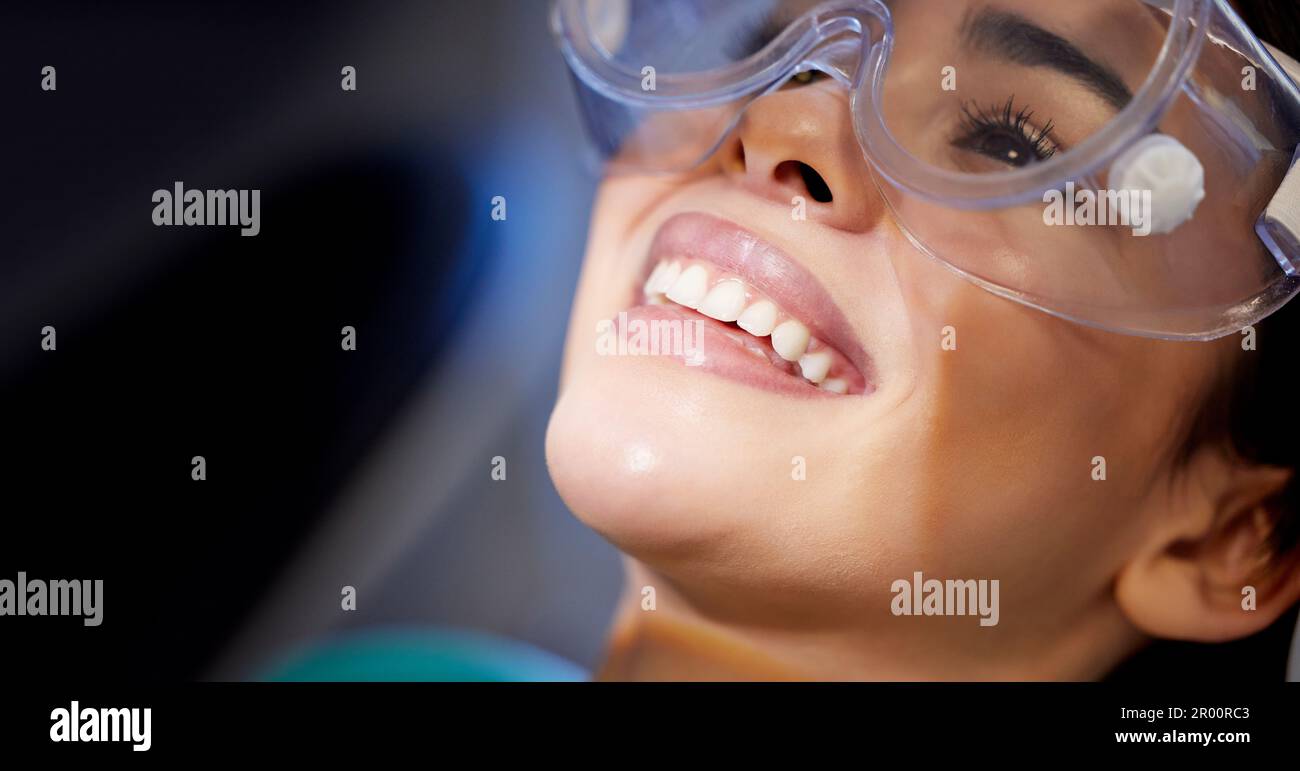 Se sent bien de sourire à nouveau. une jeune femme portant des lunettes de protection pendant une intervention dentaire. Banque D'Images