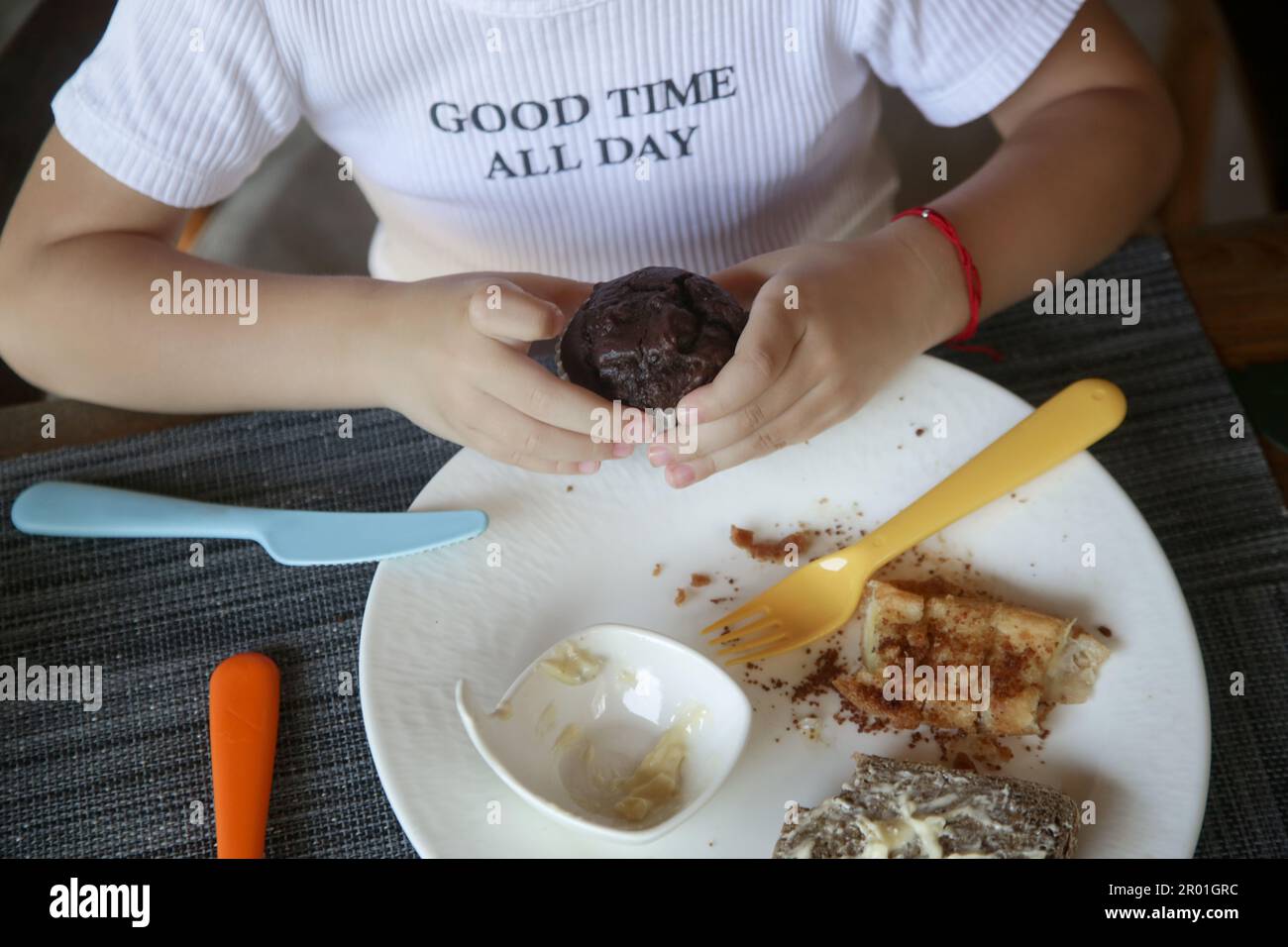 Mignonne fille de 5 ans mangeant un muffin au chocolat au restaurant Banque D'Images