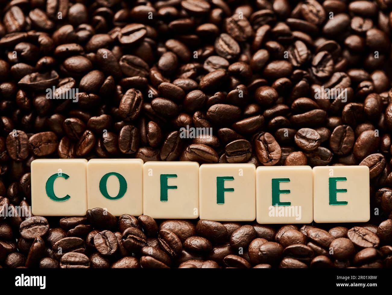 L'humanité court sur le café. Gros plan de lettres en bloc formant le mot café sur une pile de grains de café. Banque D'Images