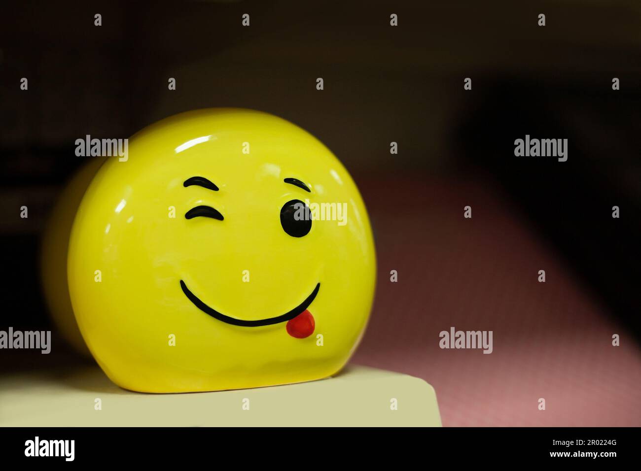 Jaune, lumineux magnifique emoji avec un sourire et une expression gaie sur un fond sombre Banque D'Images