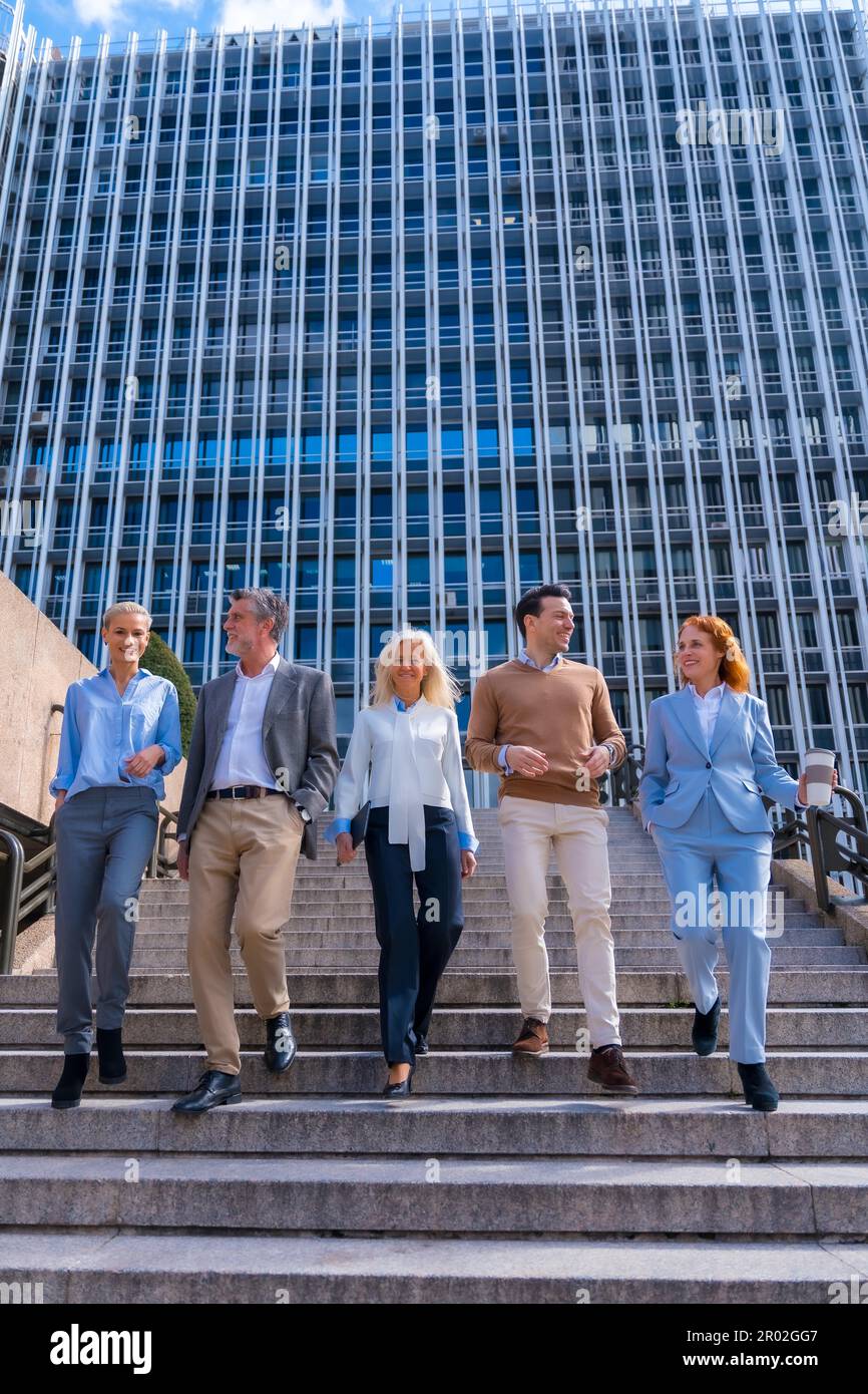 Un groupe de collègues joyeux à l'extérieur dans un bureau d'entreprise en descendant des escaliers pour aller travailler Banque D'Images