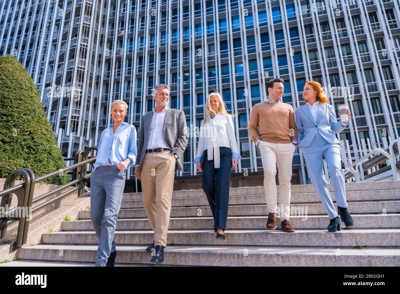 Un groupe de collègues joyeux à l'extérieur dans un bureau d'affaires en descendant quelques escaliers pour aller travailler, femme d'affaires d'âge moyen et homme d'affaires Banque D'Images