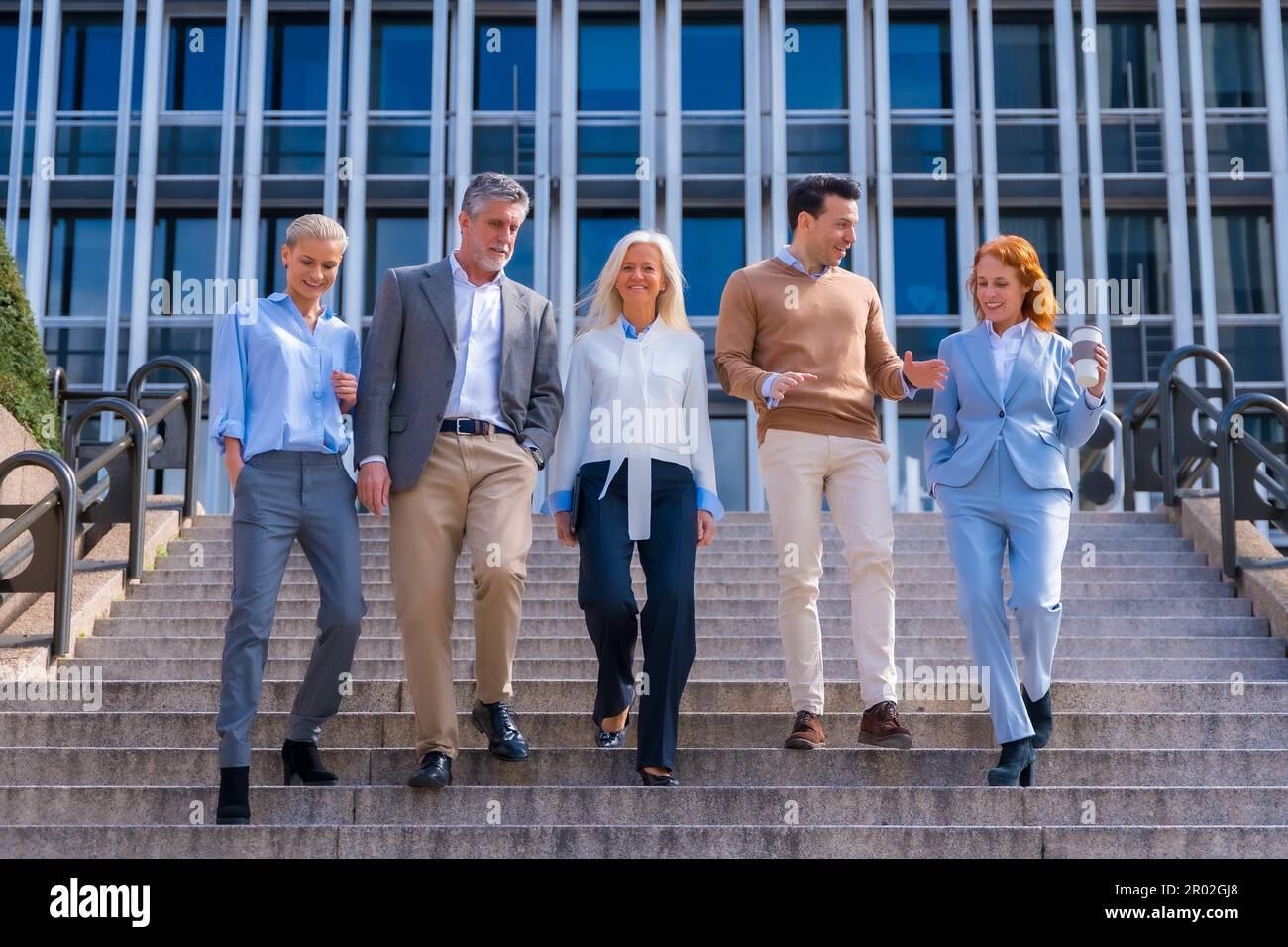 Un groupe de collègues joyeux à l'extérieur dans un bureau d'affaires en descendant quelques escaliers pour aller travailler, femme d'affaires d'âge moyen et homme d'affaires Banque D'Images