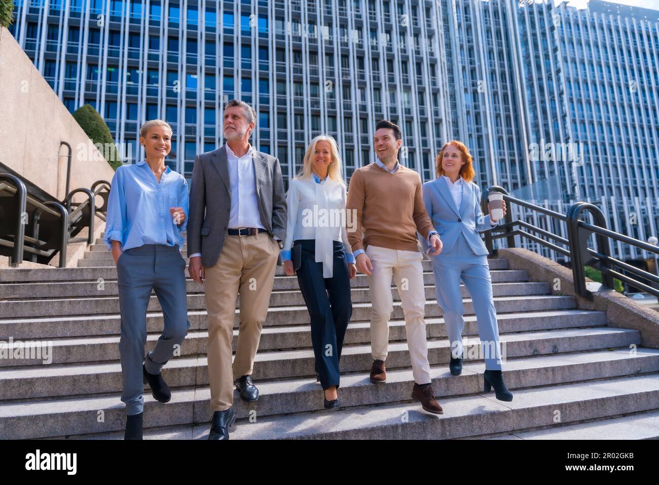 Un groupe de collègues joyeux à l'extérieur dans un bureau d'entreprise en descendant des escaliers pour aller travailler Banque D'Images