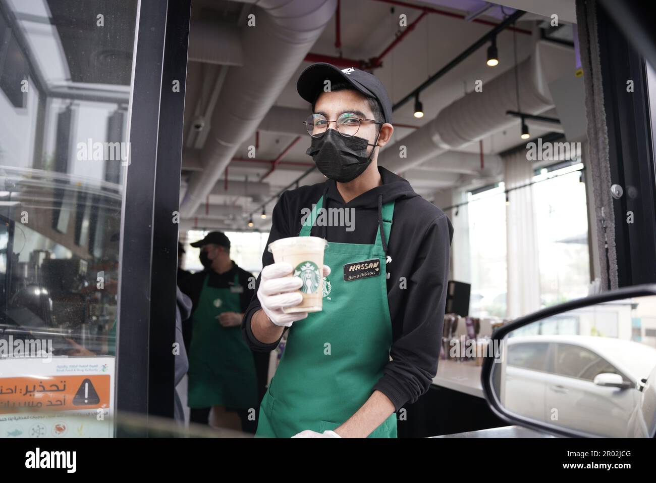 Les employés de Starbucks donnent des commandes avec des expressions du visage heureuses portant un masque facial au drive. Café moka blanc glacé. Banque D'Images