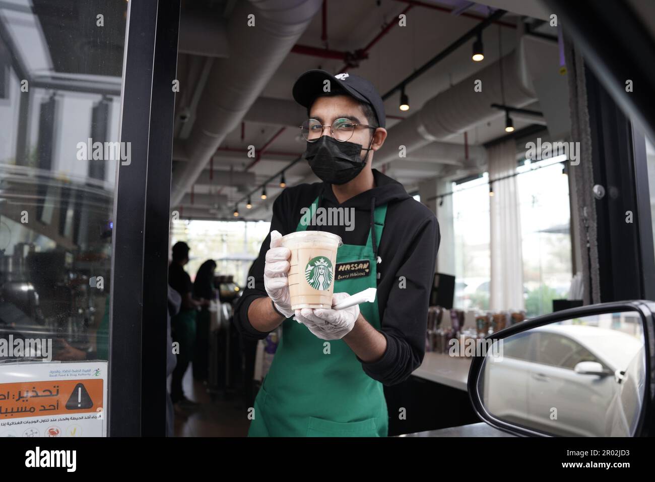 Les employés de Starbucks donnent des commandes avec des expressions du visage heureuses portant un masque facial au drive. Café moka blanc glacé. Banque D'Images