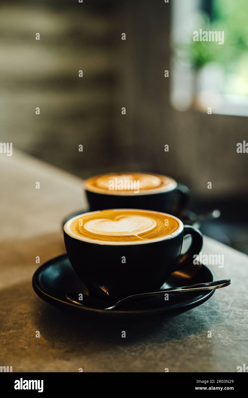 Une image rapprochée d'une tasse de café fraîchement préparé avec un latte complexe versé sur le dessus Banque D'Images