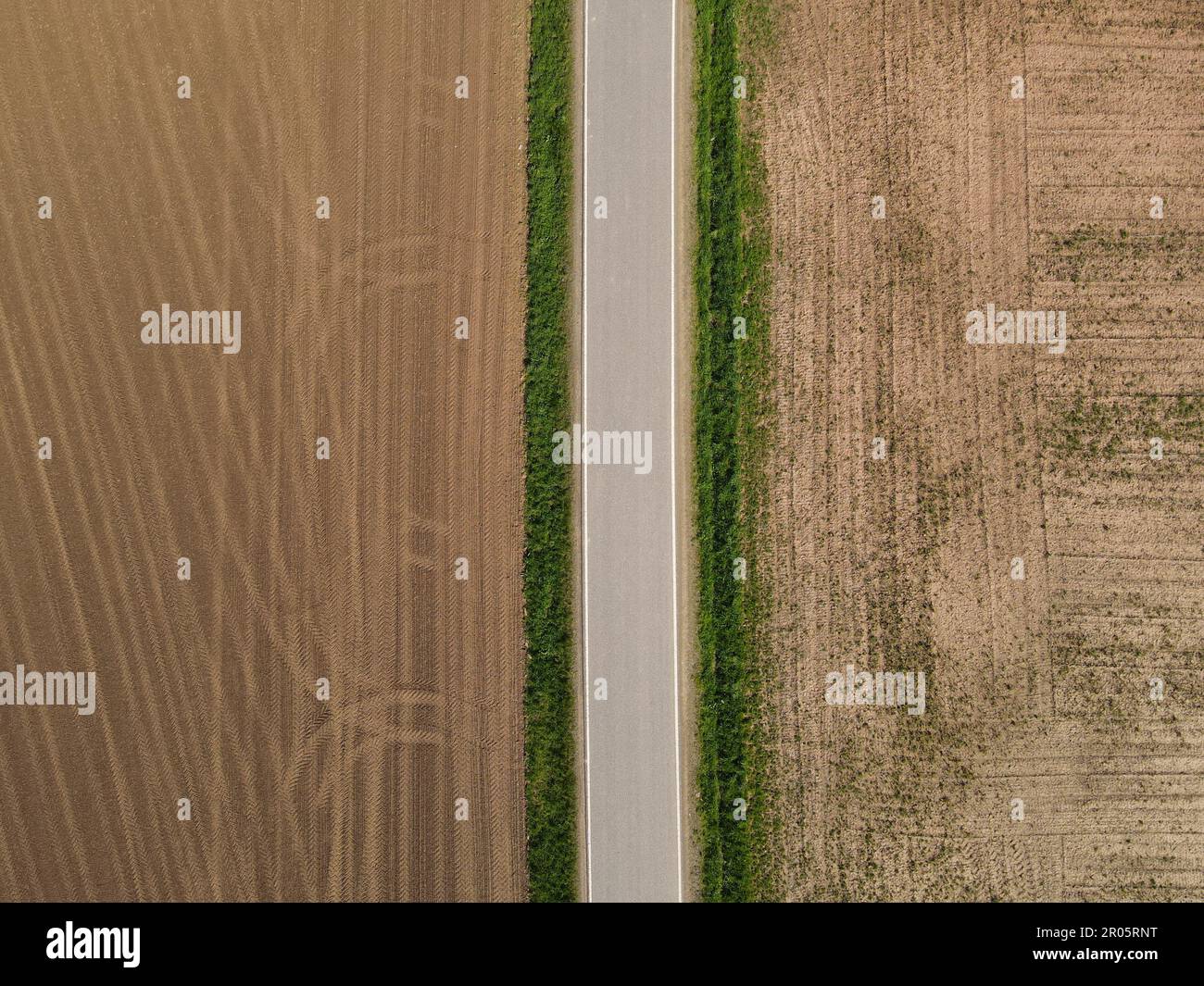 Vue depuis le dessus d'une route entre les champs agricoles labourés avec du sol dans la campagne Banque D'Images