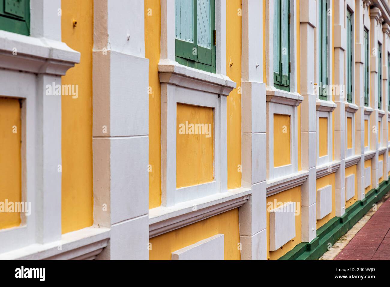 Bangkok,Thaïlande - 16 avril 2023: Le bâtiment jaune contraste avec les bandes blanches et a des fenêtres vert clair du Ministère thaïlandais de la défense. Banque D'Images