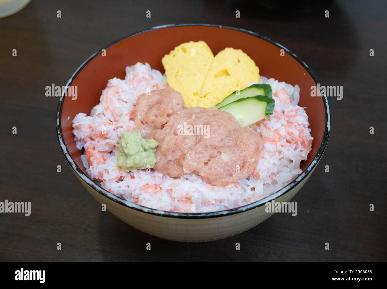 Un bol de fruits de mer avec du thon, des œufs, du riz et du concombre dans un restaurant à sushis. Banque D'Images
