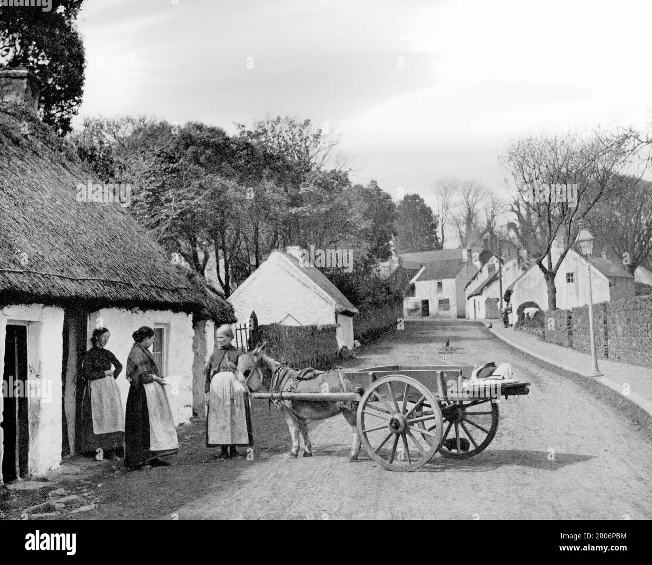 Vue de la fin du 19th siècle sur la vie de rue du village près de la côte Dublin/Wicklow, où une femme de poissons avec âne et chariot vend des produits aux habitants Banque D'Images