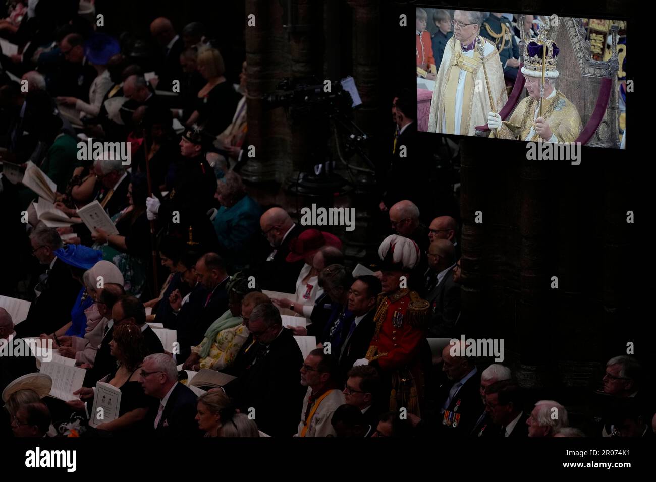 Le roi Charles III porte la couronne St Edward comme il est projeté sur un grand écran lors de sa cérémonie de couronnement à l'abbaye de Westminster à Londres. Date de la photo: Samedi 6 mai 2023. Banque D'Images