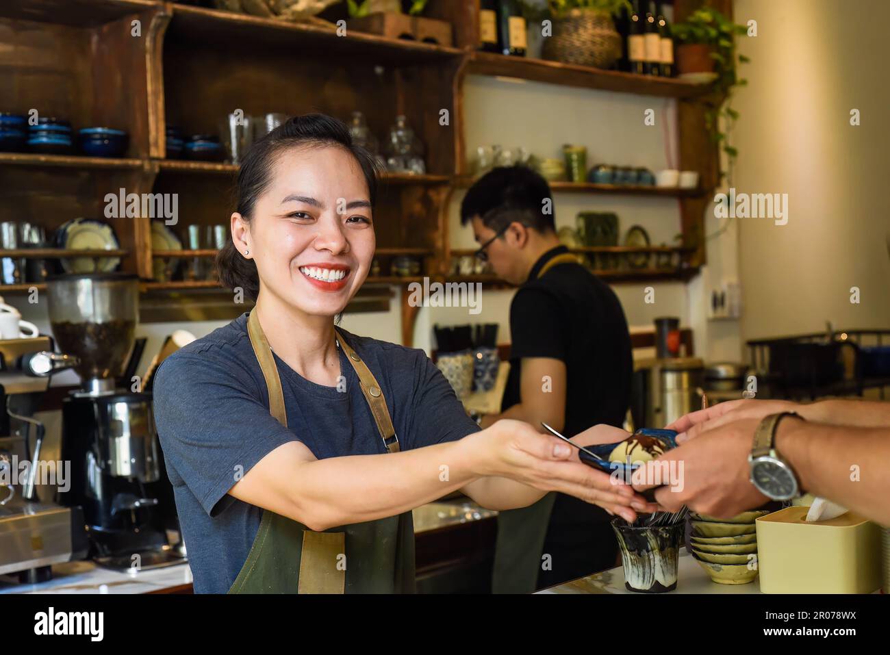 Serveuse vietnamienne servant de la crème glacée pour un client dans un café Banque D'Images