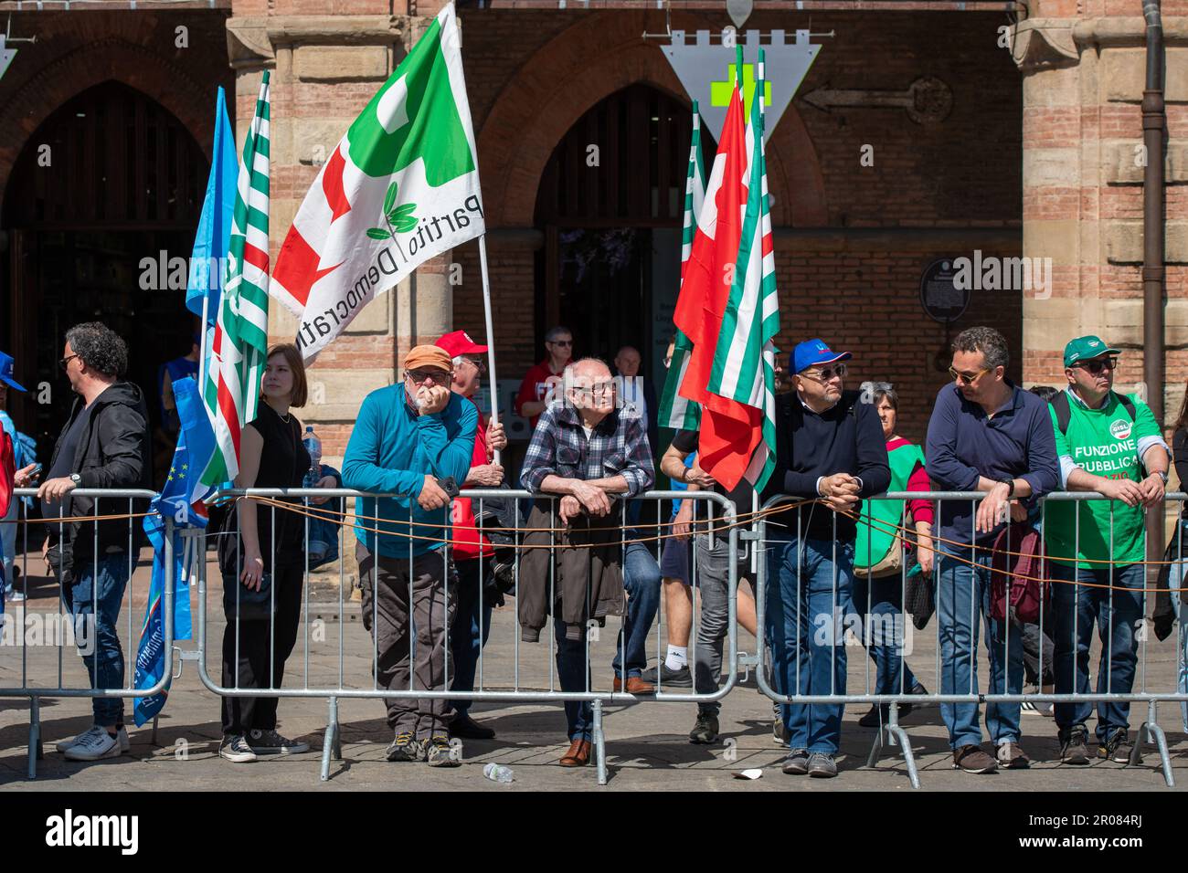 Bologne, Italie. 06th mai 2023. Un homme regarde la scène de façon consternante et un passant fait passer le drapeau du Parti démocratique en dehors de la zone de la scène des discours pendant la manifestation syndicale. 30 000 travailleurs sont descendus dans les rues de Bologne dans le cadre de la manifestation organisée par les syndicats confédéraux CGIL (Confédération générale italienne du travail), CISL (Confédération italienne des syndicats de métiers), UIL (Syndicat italien du travail) pour protester contre le décret du gouvernement Meloni sur le travail. Elly Schlein a été contestée par certains travailleurs de l'UIL pour éviter de politiser une manifestation de travailleurs. Pendant l'intervalle Banque D'Images