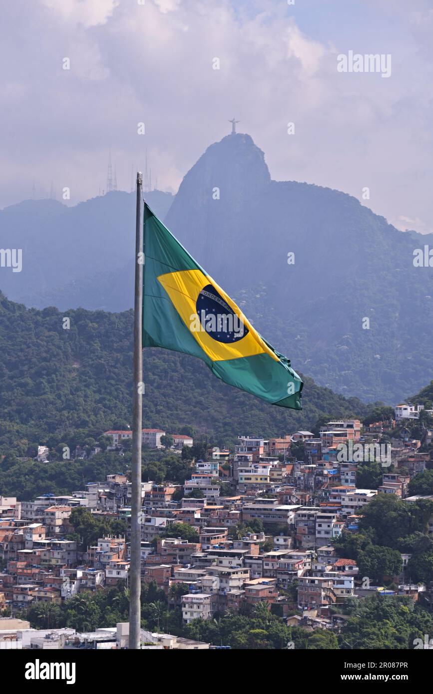 Rio de Janeiro/Brésil 05.06.2023: Drapeau du Brésil sur le mât et en arrière-plan Christ Rédempteur avec Rio de Janeiro favela dans la même scen Banque D'Images