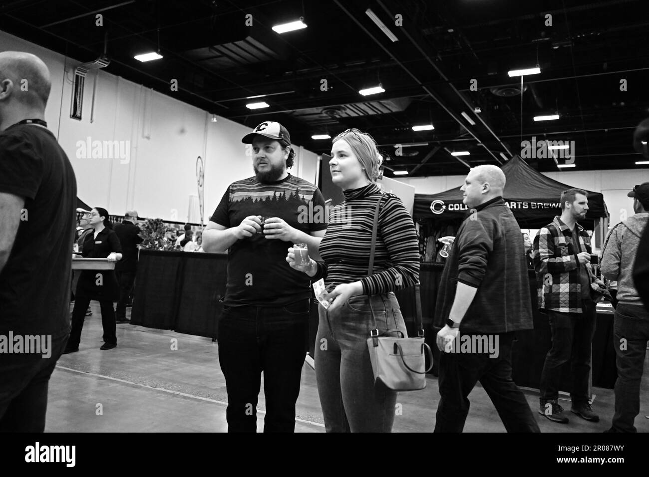 FESTIVAL DE LA BIÈRE DE CALGARY : un homme et une femme regardent l'exposition de la bière tout en tenant des tasses d'échantillon de bière. Banque D'Images