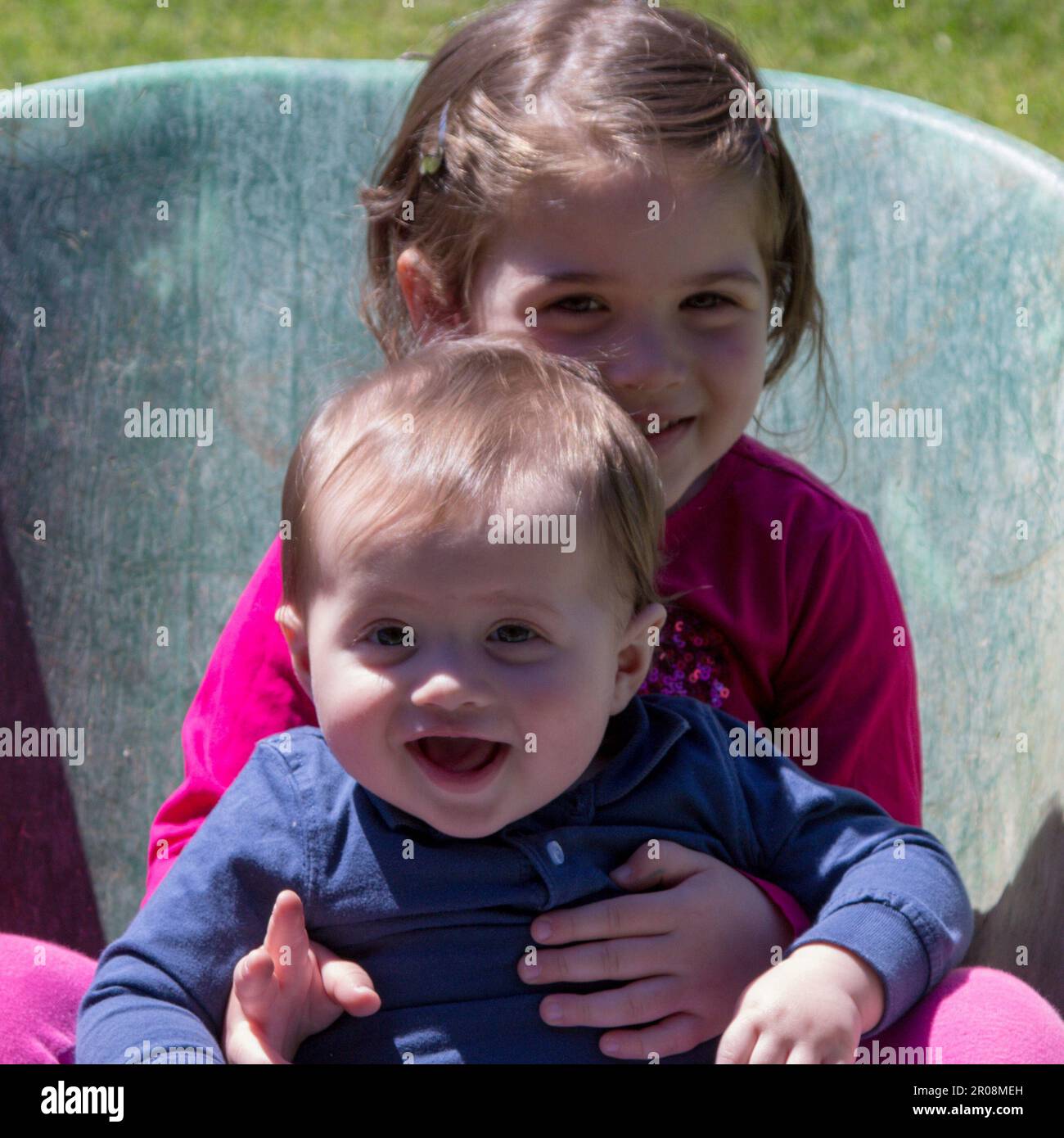 Image de deux adorables enfants souriants se tenant à l'intérieur d'une brouette. Amour fraternel comme ils jouent dans le jardin Banque D'Images