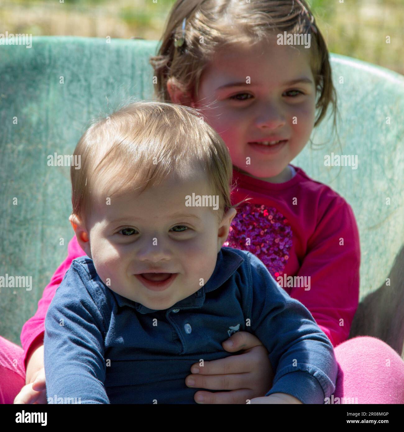 Image de deux adorables enfants souriants se tenant à l'intérieur d'une brouette. Amour fraternel comme ils jouent dans le jardin Banque D'Images