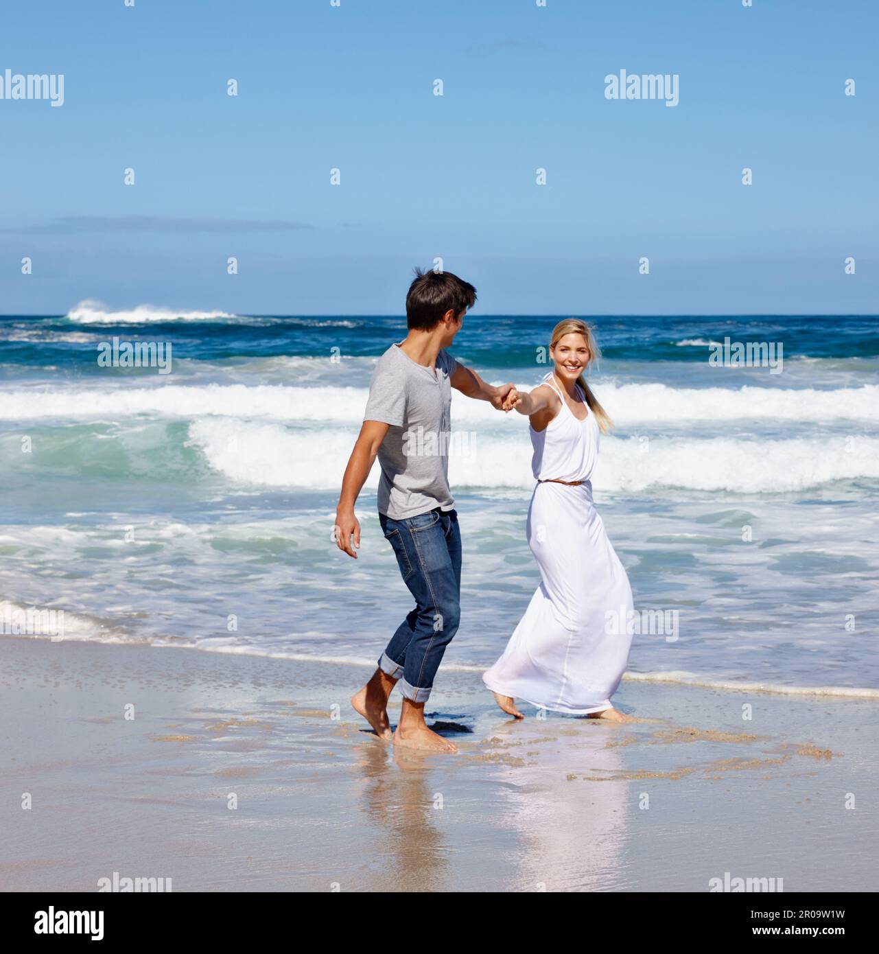 Juste un autre jour au paradis quand ils étaient ensemble. un jeune couple heureux qui profite d'une promenade le long de la plage. Banque D'Images