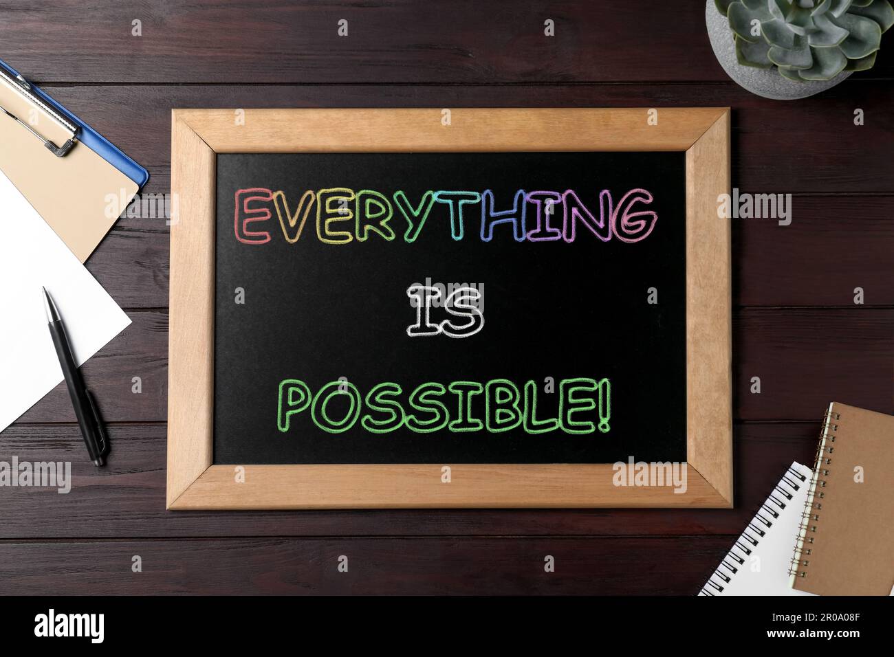 Petit tableau avec citation motivationnelle tout est possible, plante et papeterie sur table en bois, plat Banque D'Images