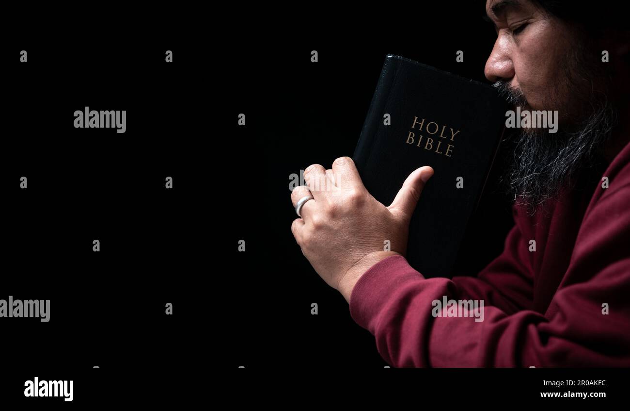 Les mains se sont repliées dans la prière sur une Sainte Bible dans le concept de foi, de spiritualité et de religion, l'homme priant le matin. Main d'homme avec la Bible prier. PE Banque D'Images