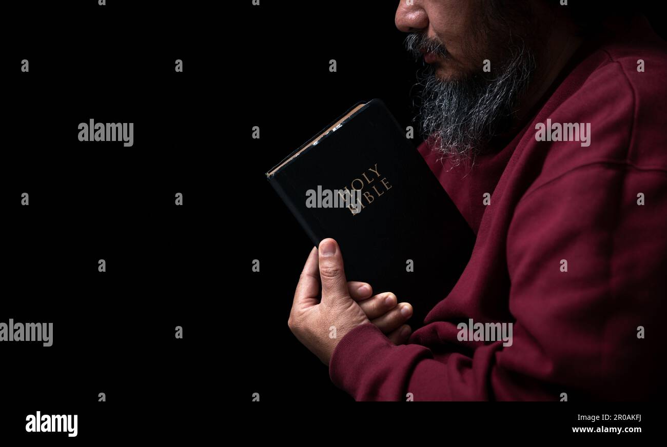 Les mains se sont repliées dans la prière sur une Sainte Bible dans le concept de foi, de spiritualité et de religion, l'homme priant le matin. Main d'homme avec la Bible prier. PE Banque D'Images