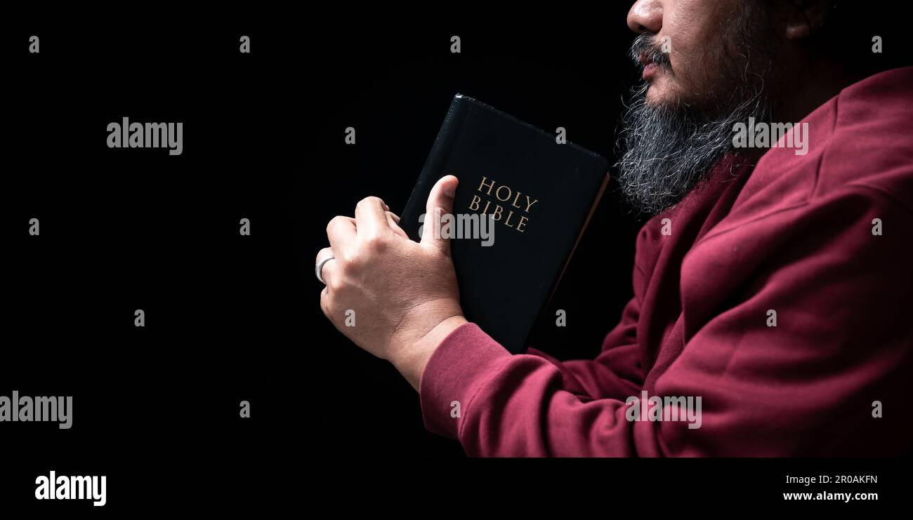 Les mains se sont repliées dans la prière sur une Sainte Bible dans le concept de foi, de spiritualité et de religion, l'homme priant le matin. Main d'homme avec la Bible prier. PE Banque D'Images
