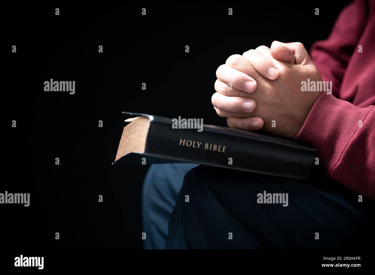 Les mains se sont repliées dans la prière sur une Sainte Bible dans le concept de foi, de spiritualité et de religion, l'homme priant le matin. Main d'homme avec la Bible prier. PE Banque D'Images