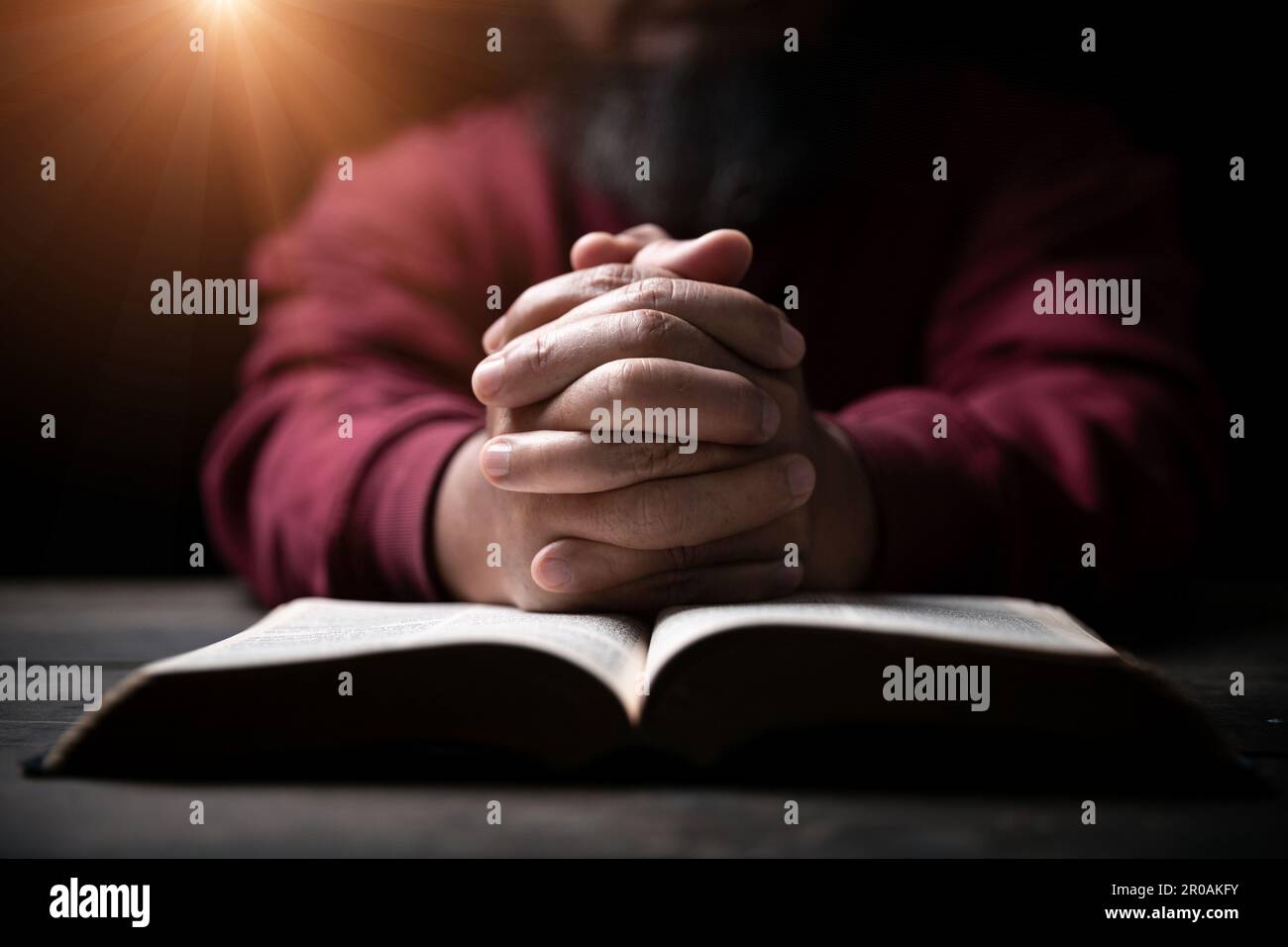 Les mains se sont repliées dans la prière sur une Sainte Bible dans le concept de foi, de spiritualité et de religion, l'homme priant le matin. Main d'homme avec la Bible prier. PE Banque D'Images