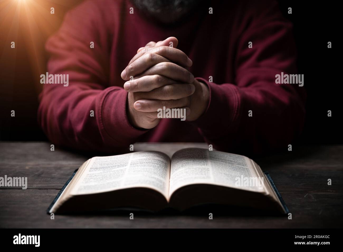 Les mains se sont repliées dans la prière sur une Sainte Bible dans le concept de foi, de spiritualité et de religion, l'homme priant le matin. Main d'homme avec la Bible prier. PE Banque D'Images
