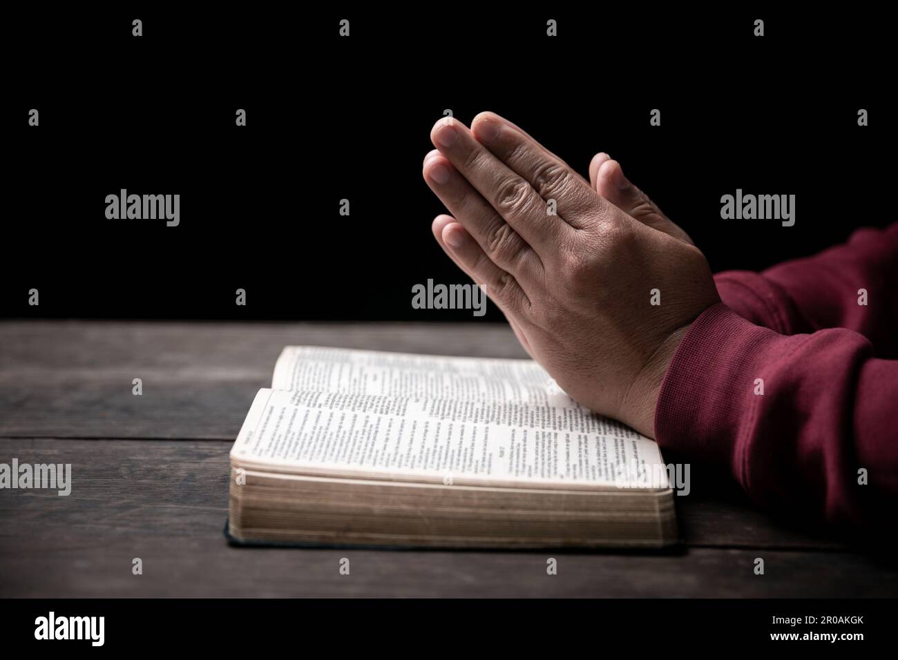 Les mains se sont repliées dans la prière sur une Sainte Bible dans le concept de foi, de spiritualité et de religion, l'homme priant le matin. Main d'homme avec la Bible prier. PE Banque D'Images