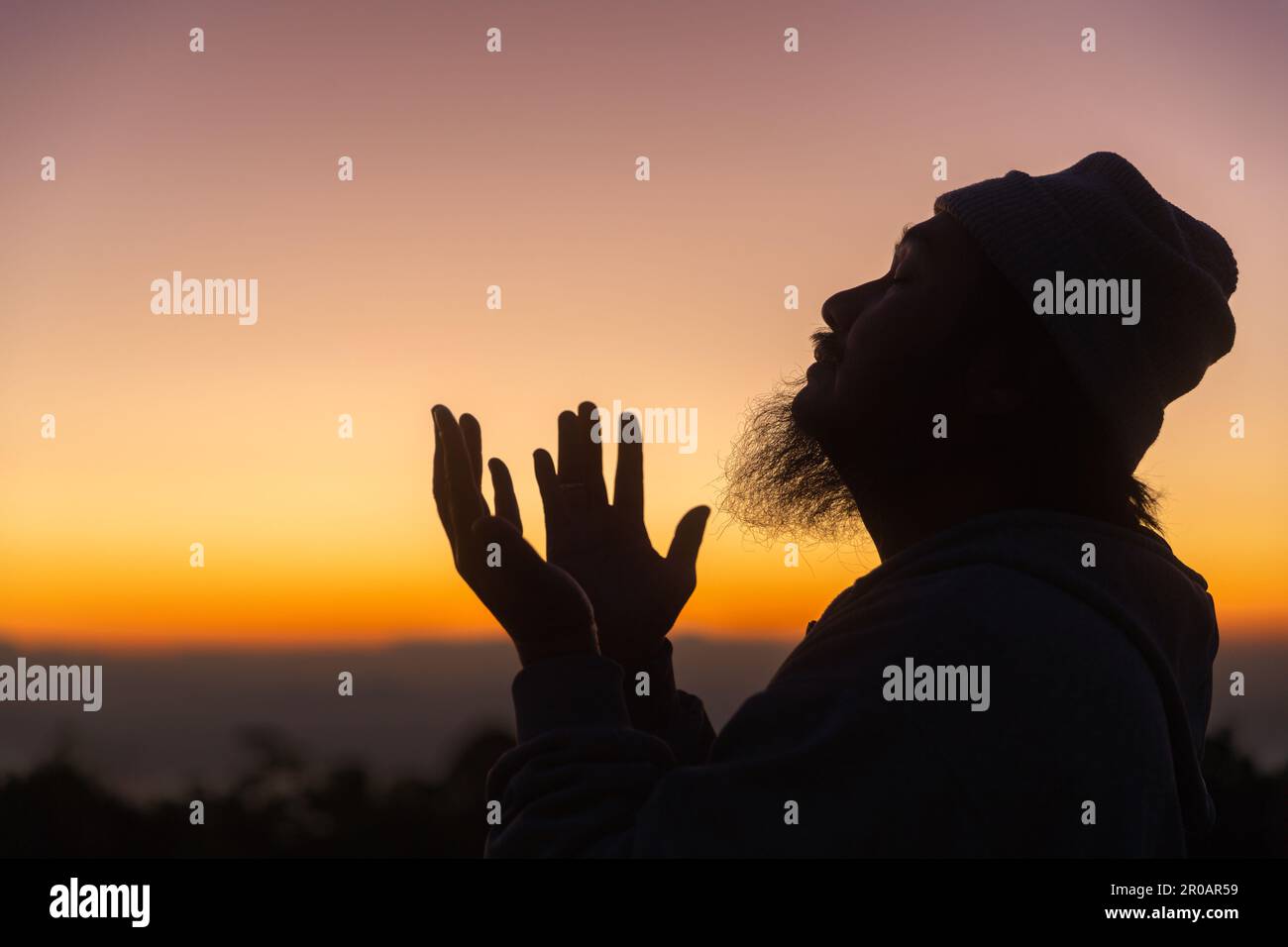 Silhouette de l'homme s'agenouillant en priant pour l'adoration de Dieu sur fond de ciel. Les chrétiens prient à jésus-christ pour le calme. Le matin, les gens sont arrivés à une quil Banque D'Images