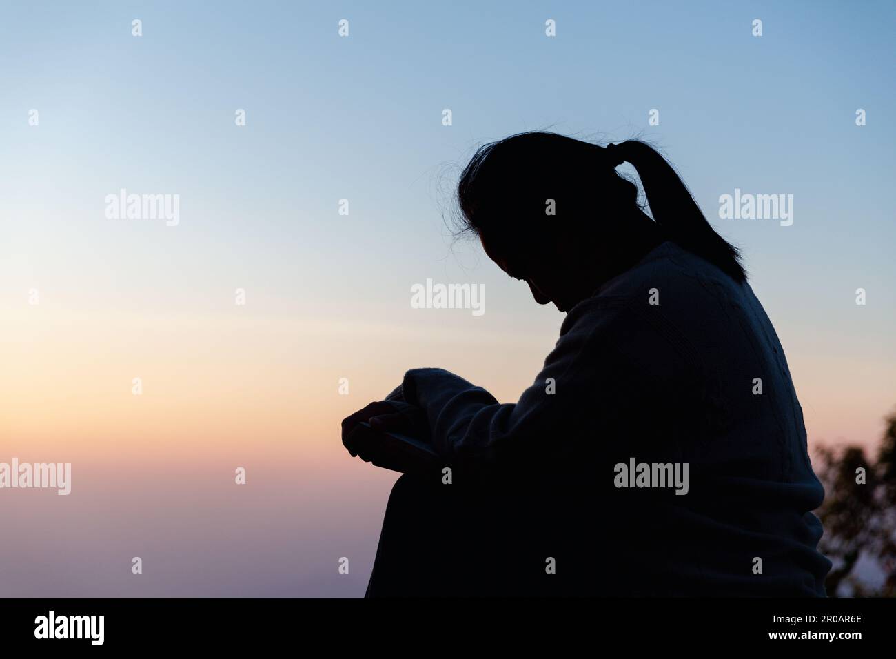 Silhouette de femme s'agenouillant en priant pour l'adoration de Dieu sur fond de ciel. Les chrétiens prient à jésus-christ pour le calme. "Le matin, les gens ont atteint un. Banque D'Images