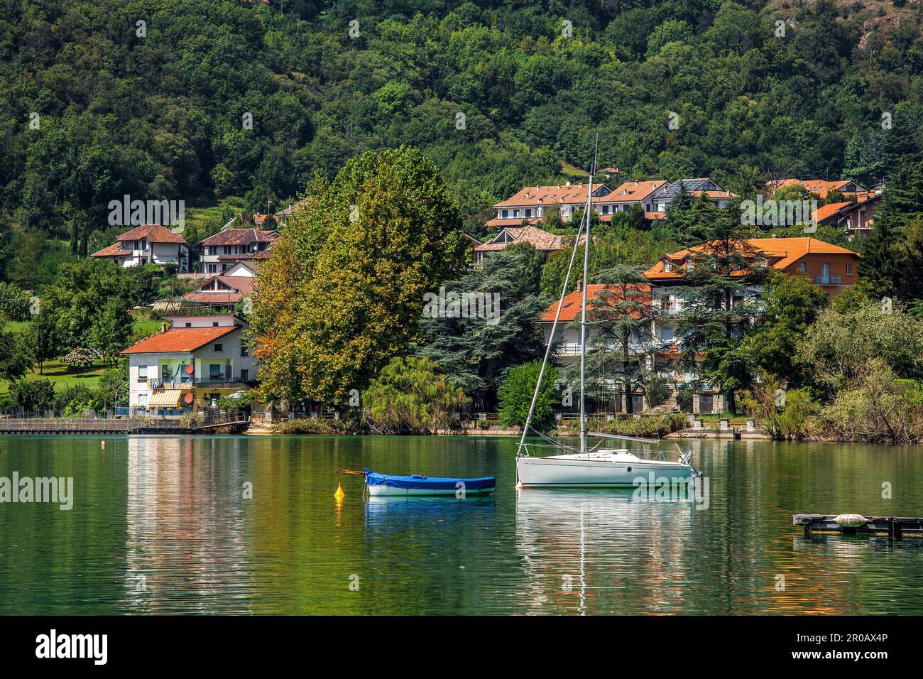 Vue sur le yacht et le bateau et la petite ville parmi les arbres verts sur le lac Avigliana dans le nord de l'Italie. Banque D'Images