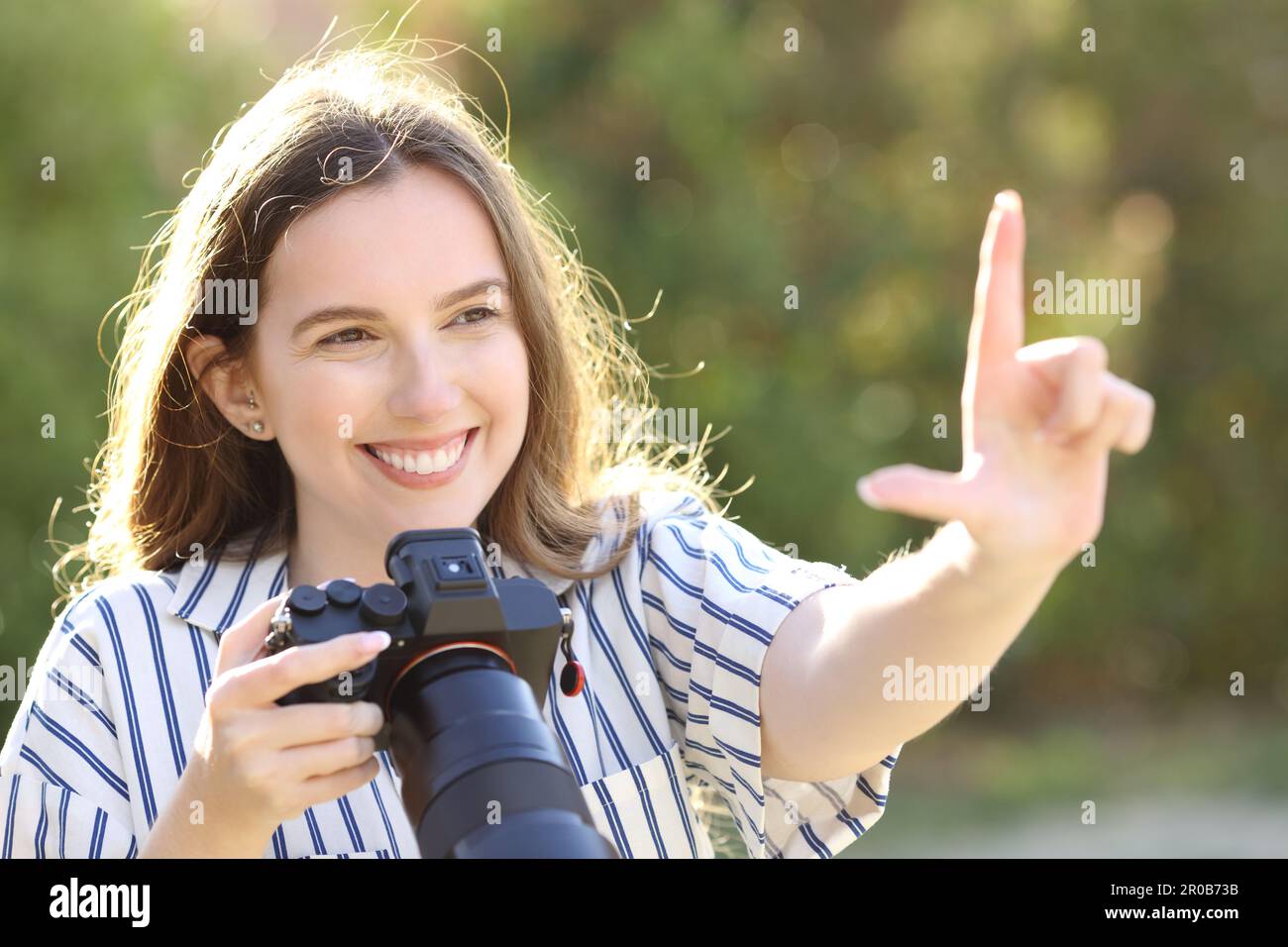 Bonne photographe calculant le cadre avec sa main tenant l'appareil photo sans miroir Banque D'Images