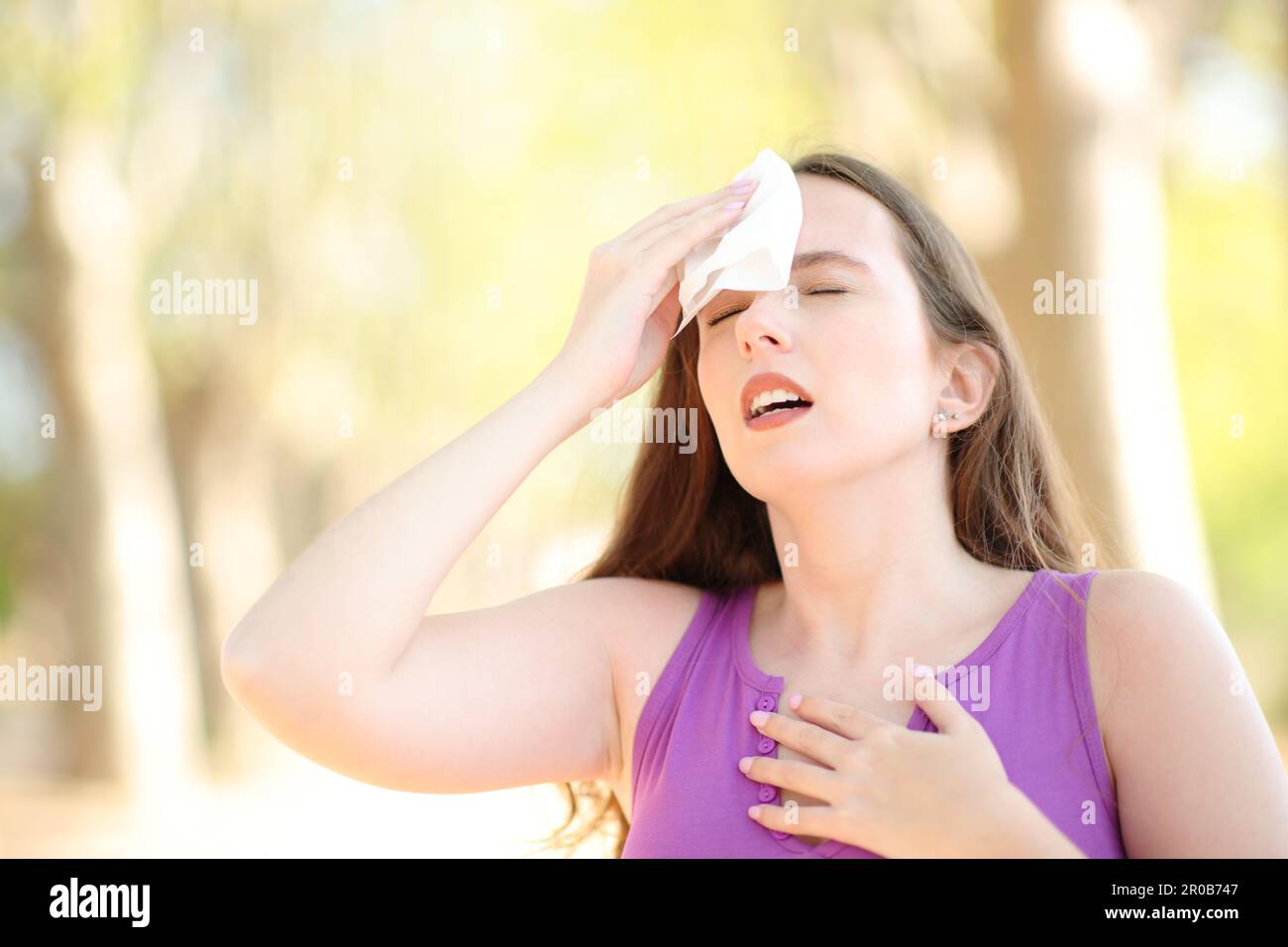 Femme stressée qui sèche la sueur un jour chaud de l'été dans un parc Banque D'Images