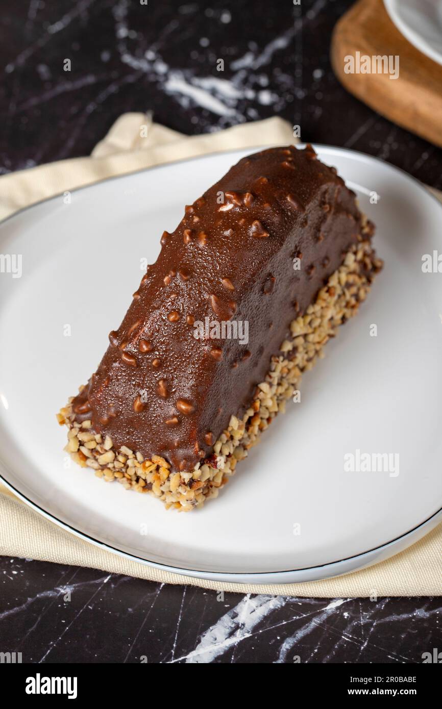 Gâteau à la banane et au chocolat. Gâteau de malaga recouvert de chocolat et noisette sur fond sombre. Gros plan Banque D'Images