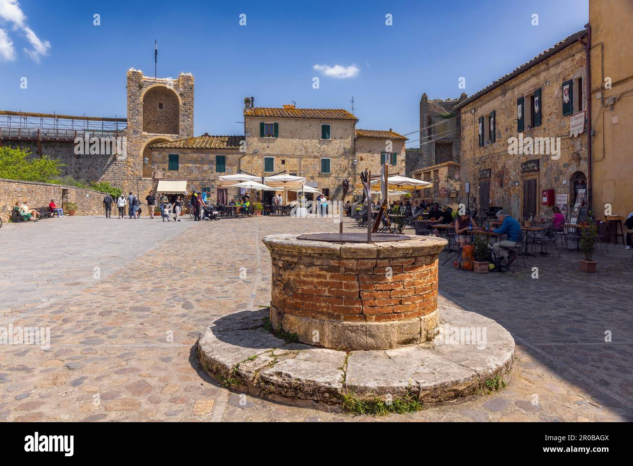 Monteriggioni, province de Sienne, Toscane, Italie. La citerne de la Piazza Roma et en arrière-plan la tour au-dessus de la porte principale de la ville fortifiée. Banque D'Images