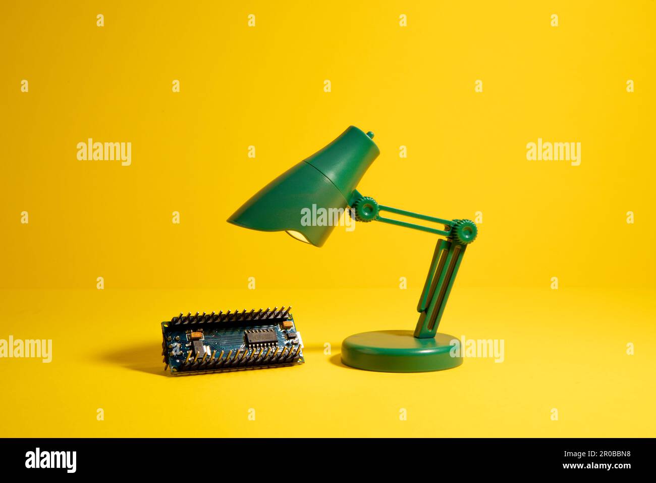 Carte électronique illuminée par une lampe à jouets sur fond jaune. Banque D'Images