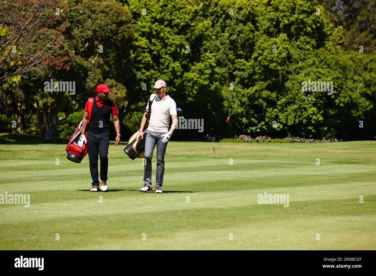 Qui a besoin d'un caddy avec votre ami marchant à côté de vous. deux hommes portant leurs sacs de golf sur un parcours de golf. Banque D'Images