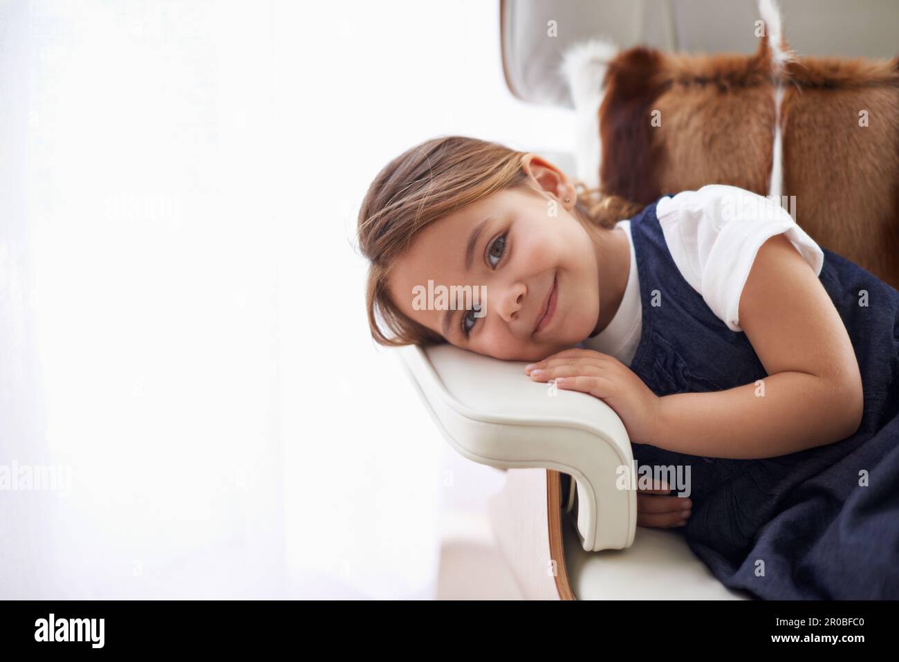 Je vais être une grande fille un jour. Portrait d'une adorable petite fille qui pose la tête sur l'accoudoir d'une chaise. Banque D'Images