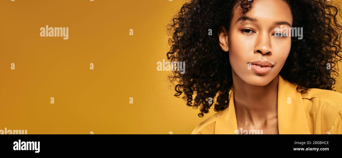 Belle femme afro-américaine avec une coiffure maurique, de beaux yeux et des lèvres plumeuses regardant l'appareil photo, portrait de studio sur fond jaune Banque D'Images